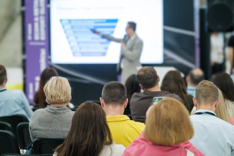 A conference uses a themed backdrop for presentations.