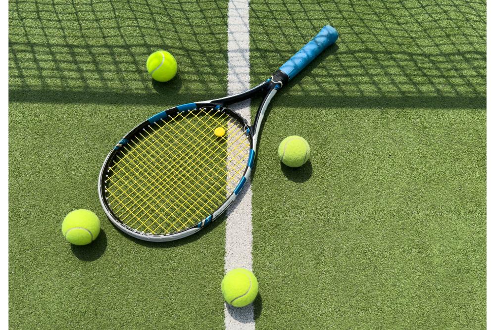 ไม้และลูกเทนนิสในสนามเทนนิสกลางแจ้ง